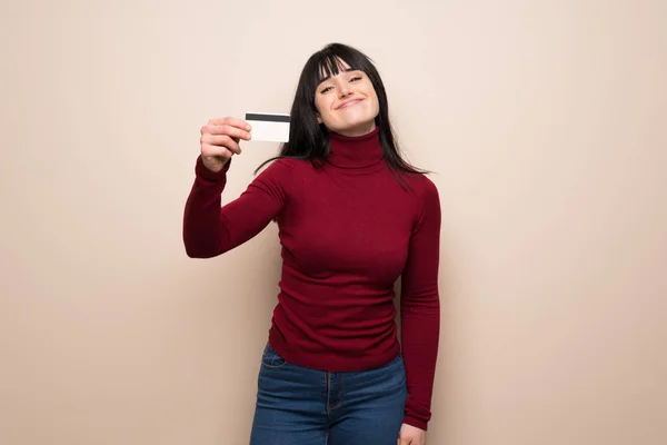 Young woman with red turtleneck holding a credit card