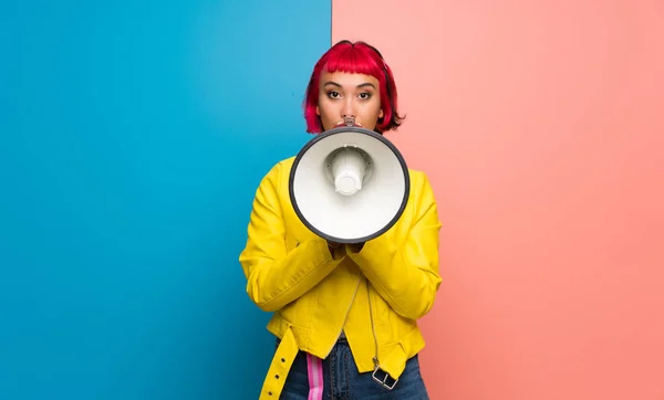 Young woman with yellow jacket shouting through a megaphone