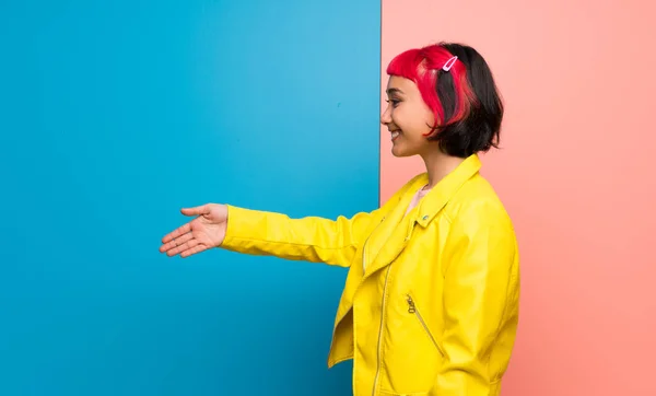 Young woman with yellow jacket handshaking after good deal