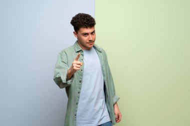 Mavi ve yeşil arka plan ciddi ve ön işaret eden genç adam