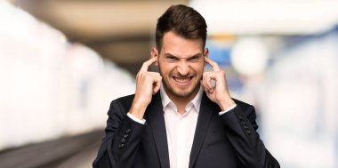 Hayal kırıklığına uğramış ve kulakları el ile kapalı kapsayan yakışıklı iş adamı