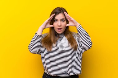 Sürpriz ifade ile sarı duvarın üzerinden genç kız