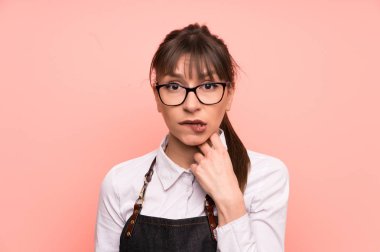 Genç garson şüpheleri pembe bir arka plan üzerinde ve karıştırmayın yüz ifadesi ile