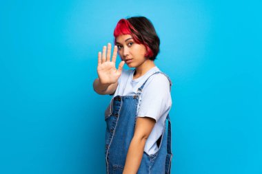 Mavi duvar yapma dur jest ve hayal kırıklığına pembe saçlı genç kadın