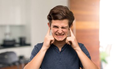 Hayal kırıklığına uğramış ve kulakları el ile kapalı kapsayan genç adam