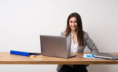 İş kadını kollarına kalça ile poz ve gülümseyen bir ofiste