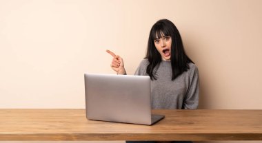 Laptopunu şaşırttı ve yan işaret ile çalışan genç kadın