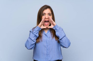 Genç kız bağırarak ve bir şey ilan izole mavi duvarın üzerinden