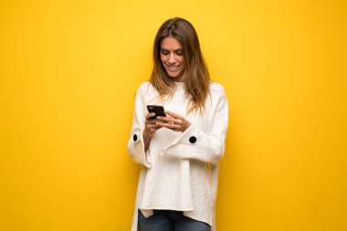 Sarışın kadın sarı duvar mobil ileti gönderme