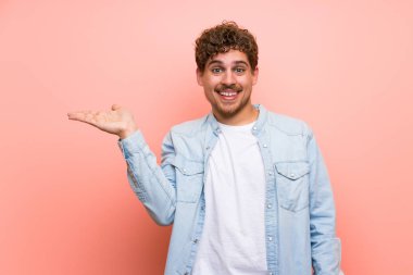 Sarışın adam pembe duvar boşaltmak hayali avuç içinde tutan bir reklam eklemek için