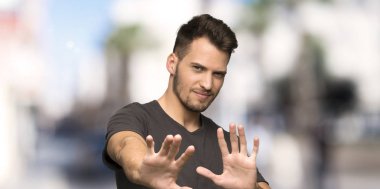 Gergin ve korkmuş siyah gömlek germe ile adam açık havada cephede eller