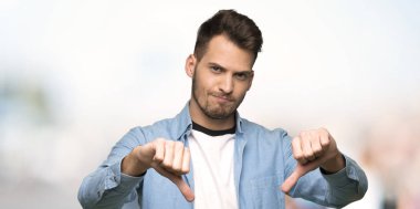 Yakışıklı adam açık havada başparmak aşağı gösterilen