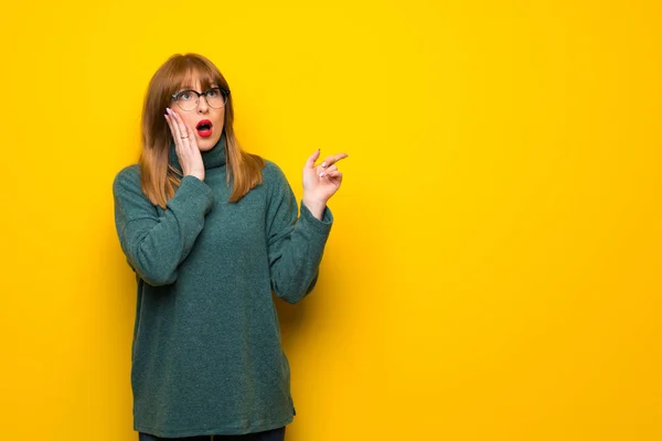 Žena Brýlemi Nad Žluté Zdi Směřující Nahoru Překvapený — Stock fotografie