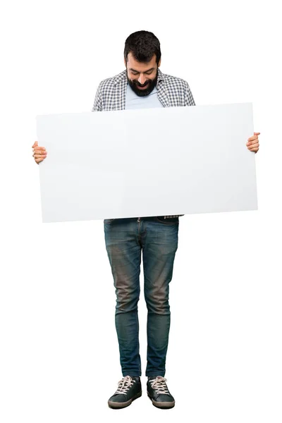Homem bonito com barba segurando um cartaz vazio — Fotografia de Stock
