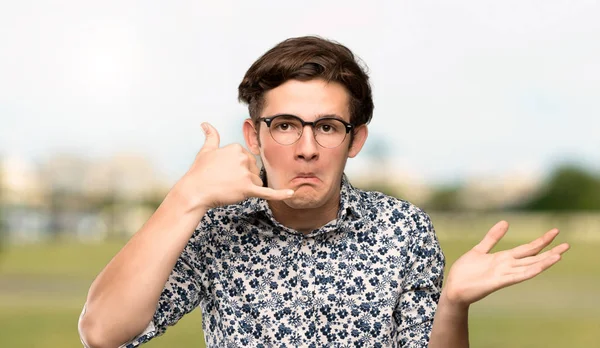 Tiener Man Met Bloem Shirt Glazen Telefoon Gebaar Maken Twijfelen — Stockfoto