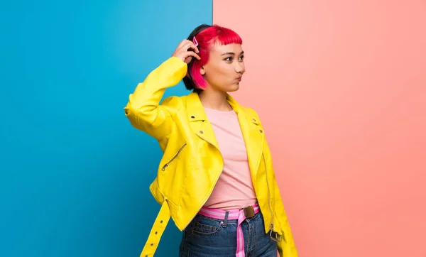 Young woman with yellow jacket having doubts while scratching head