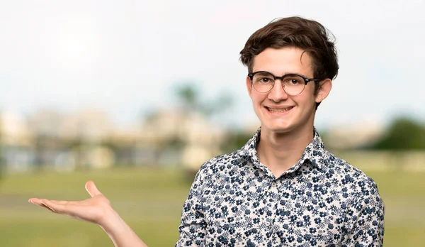 Dospívající Muž Květina Košili Brýle Drží Imaginární Copyspace Dlani Vložit — Stock fotografie