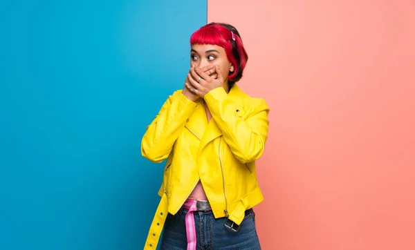 Young woman with yellow jacket covering mouth with hands