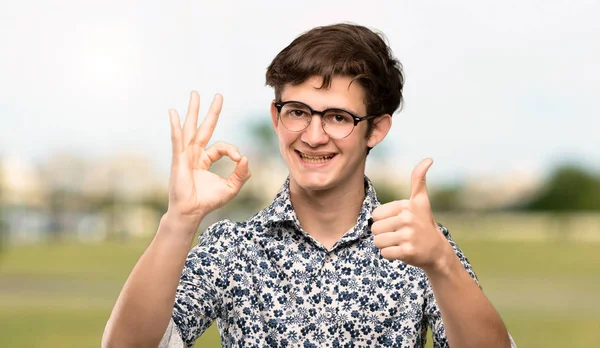 Adolescente Homem Com Camisa Flor Óculos Mostrando Sinal Com Dando — Fotografia de Stock