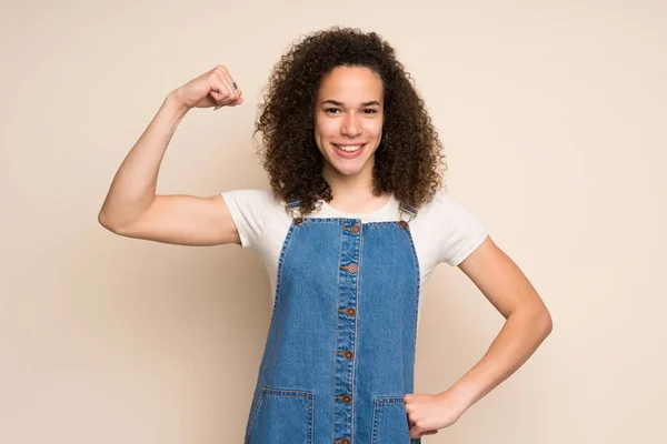 Dominican woman with overalls doing strong gesture