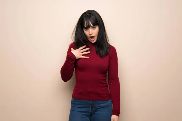 Young woman with red turtleneck surprised and shocked while looking right