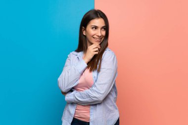 Pembe ve mavi duvar tarafına el ile çeneme arıyorum genç kadın