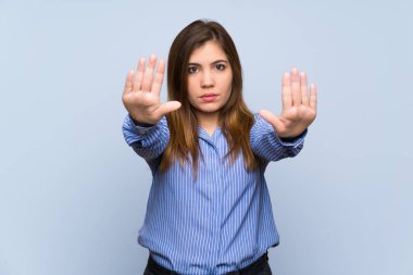 Genç kız üzerinde mavi duvar dur jest yapma izole ve hayal kırıklığına