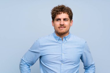 Sarışın adam karıştırmayın yüz ifadesi ile mavi duvarın üzerinden