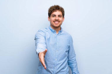 Mavi duvar iyi bir anlaşma kapanış tokalaşırken sarışın adam