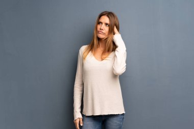 Parmak kafasına koyarak delilik jest yapma gri arka plan üzerinde sarışın kadın