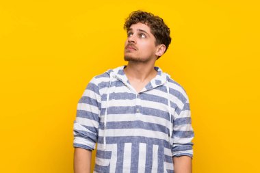 Sarışın adam sarı duvar ile ciddi bir yüz ararken