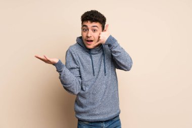 İzole duvar üzerinde genç adam telefon jest yapma ve şüphe