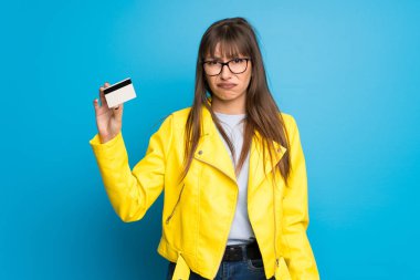 Bir kredi kartı olmadan para alarak mavi zemin üzerine sarı ceket Bayan