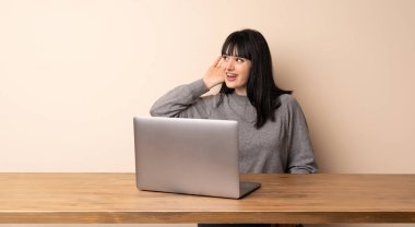 Bir şey kulak el koyarak dinleme onu laptop ile çalışan genç kadın