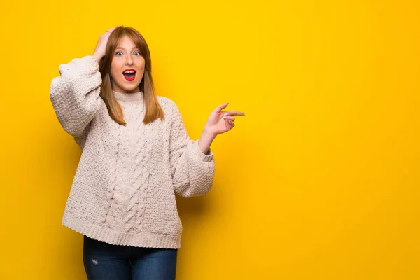 赤毛の女性側に黄色の壁に驚くとポインティング指上 — ストック写真