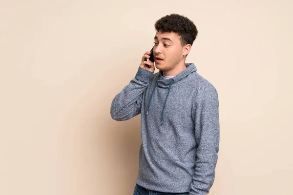Mladý Muž Nad Izolovanou Stěnou Který Udržuje Rozhovor Mobilním Telefonem — Stock fotografie