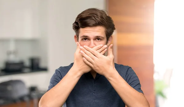 Teenager man covering mouth with hands for saying something inappropriate at indoors