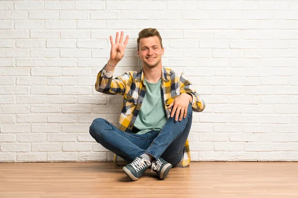 Blond Man Sitter Golvet Glad Och Räknar Fyra Med Fingrar — Stockfoto