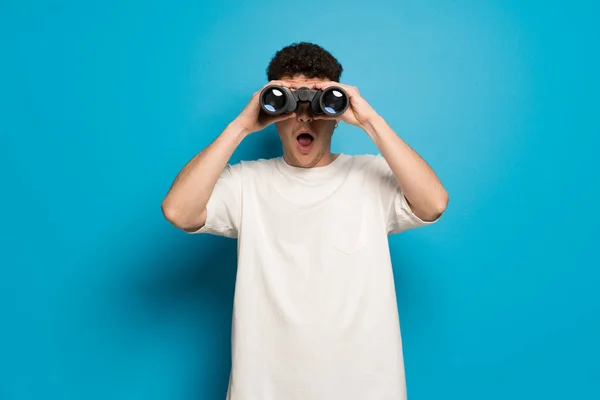 Jonge Man Blauwe Achtergrond Kijken Verte Met Verrekijker — Stockfoto