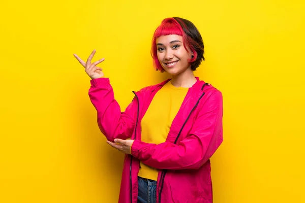 Νεαρή Γυναίκα Ροζ Μαλλιά Πάνω Από Κίτρινο Τοίχο Επεκτείνοντας Χέρια — Φωτογραφία Αρχείου