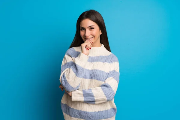 Young woman over blue wall smiling and looking to the front with confident face