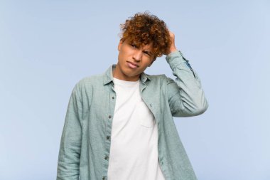 Genç Afro-Amerikan adam, mavi duvarın ötesinde, kafasını kaşıyarak şüpheleri var.