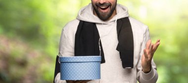 Spor adam bir parkta elinde hediye kutusu tutarak