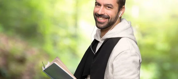 Sport man holding a book and enjoying reading in a park