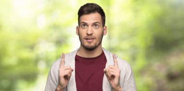 Sweatshirt ile adam yukarı işaret ve bir parkta şaşırdı