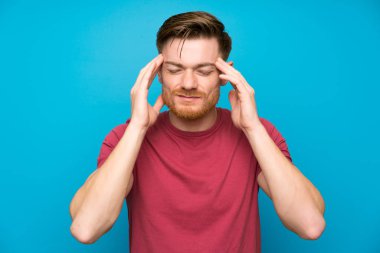Izole mavi duvarda Kızıl saçlı adam mutsuz ve bir şey ile sinirli. Negatif yüz ifadesi