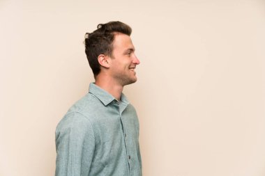 Sarışın yakışıklı adam ayakta ve tarafına bakarak izole duvarın üzerinden