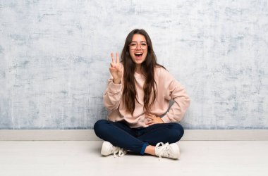 Genç öğrenci kız bir tablo gülümseyen ve zafer işareti gösteren okuyan