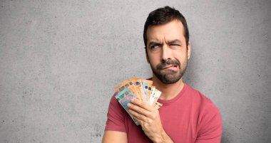 Adam karıştırma yüz ifadesi ile çok para alarak dokulu duvar üzerinde dudak ısırık sırasında