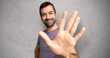 Yakışıklı adam beş parmak ile dokulu duvar üzerinde sayma